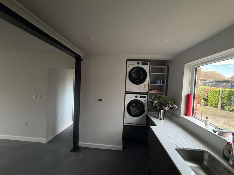 Kitchen and utility area with fresh white walls and a black beam