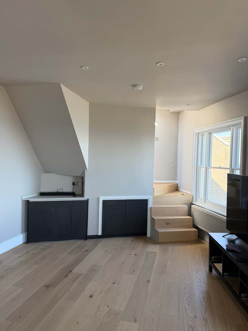 Loft living space with pale walls, a short staircase and an oak floor